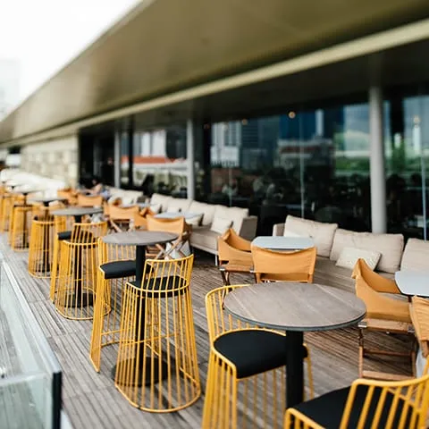 A restaurant with yellow chairs and tables on a wooden deck.