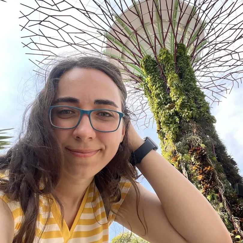 A woman in glasses is taking a selfie in front of a tree in singapore.