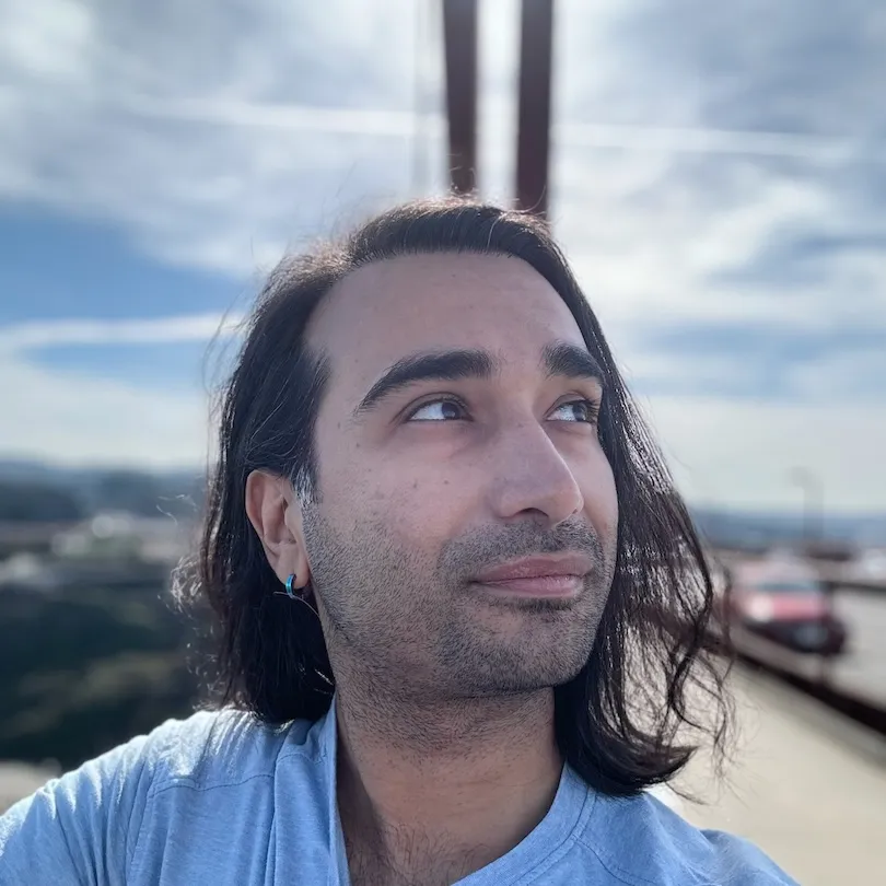 A man with long hair standing on top of a bridge.